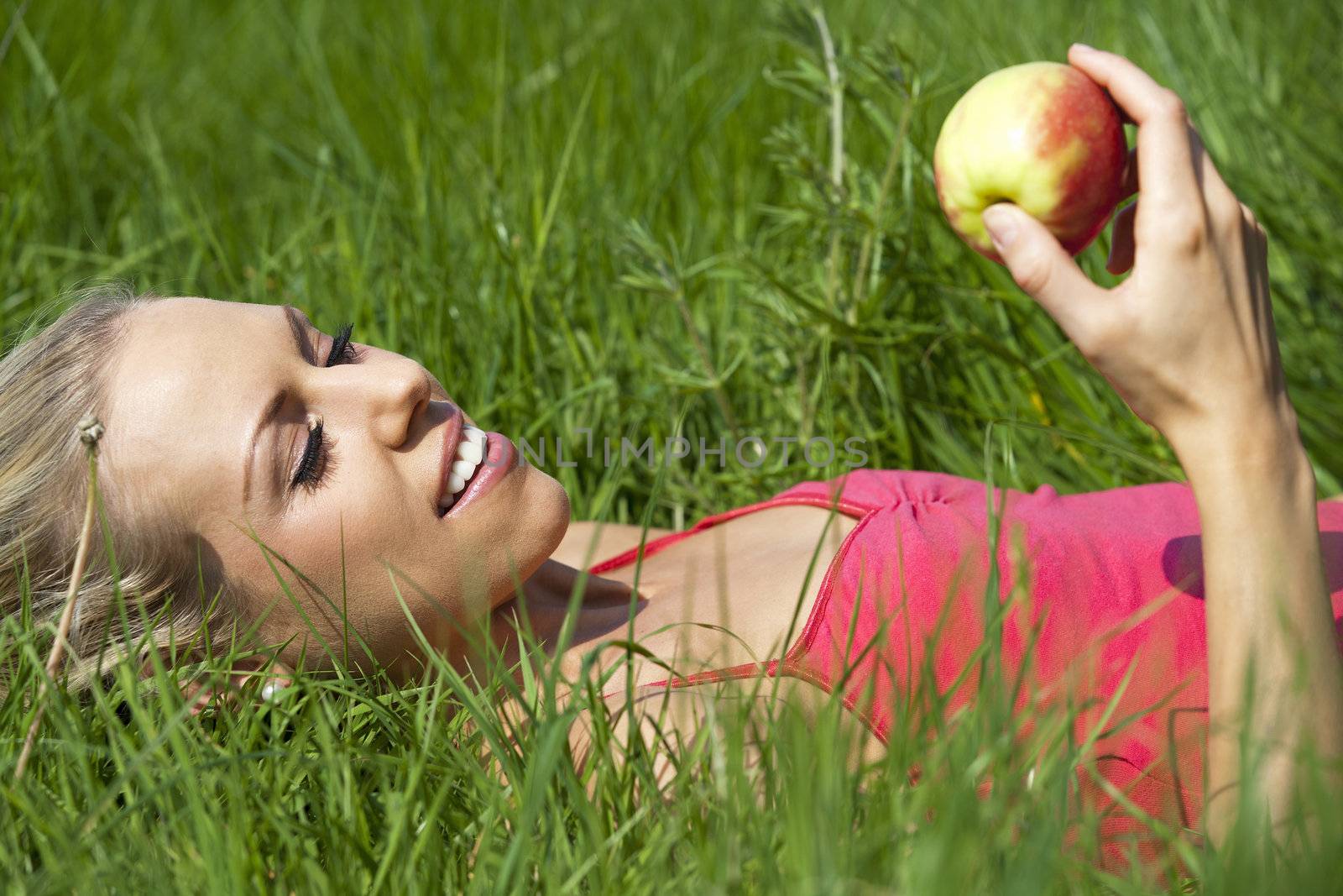 Woman in field eating an apple by studiofi