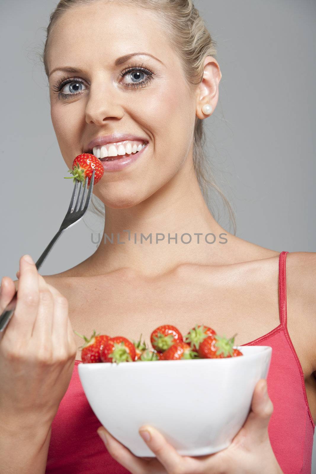 Beautiful young woman eating fresh summer berries