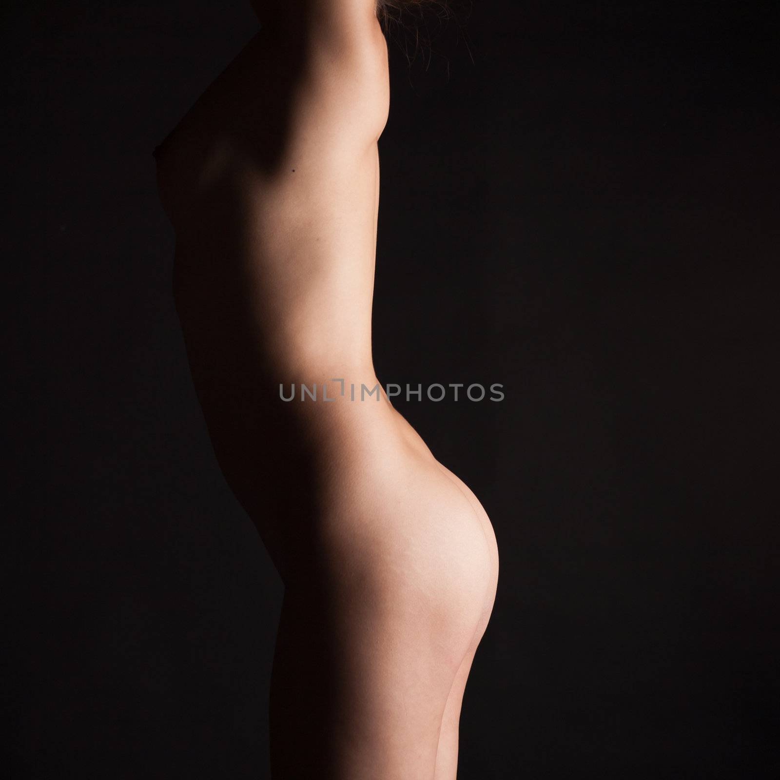 Naked body of a teenage girl. On a black background.