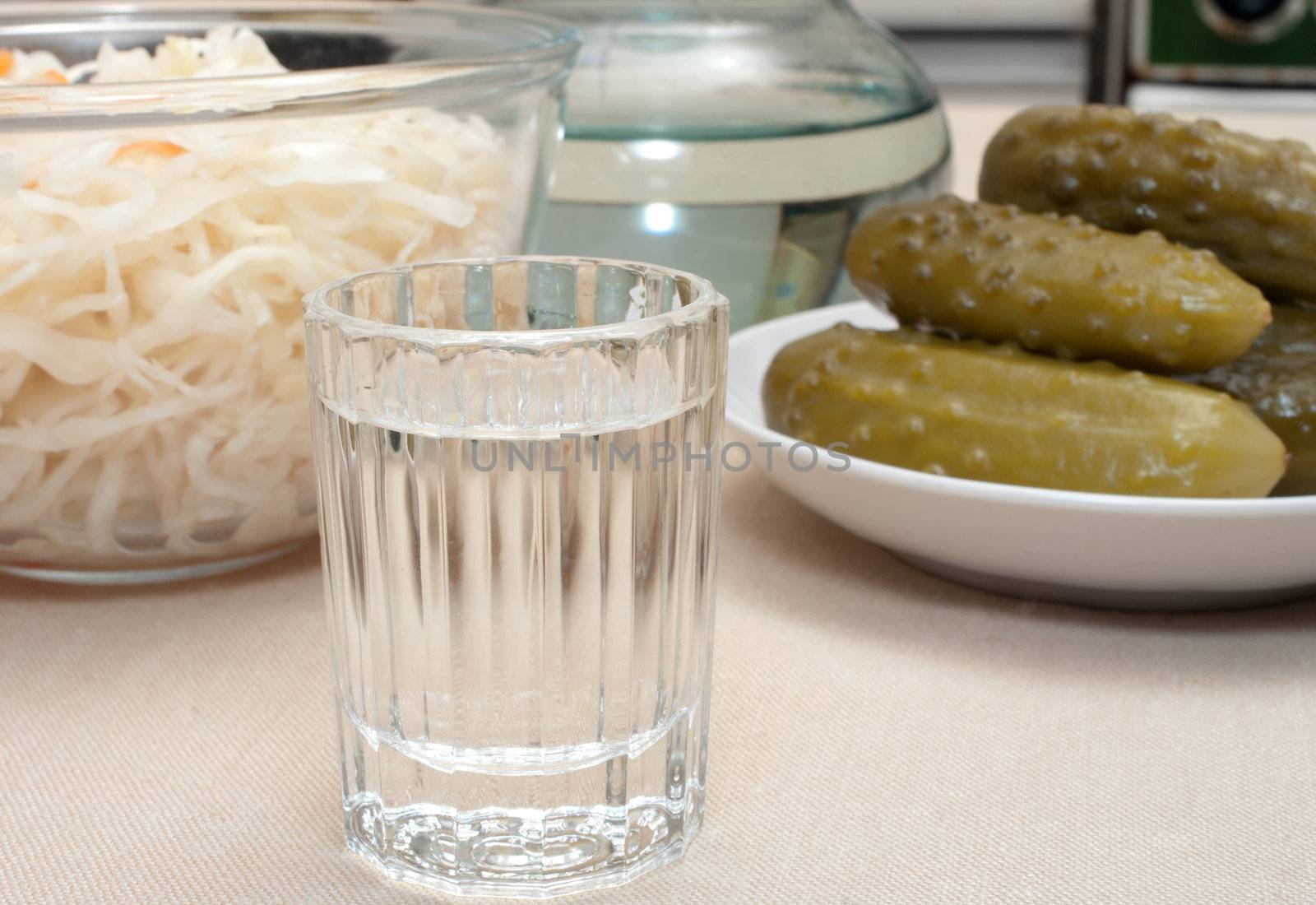 Wine-glass of vodka pickles and sauerkraut close up.