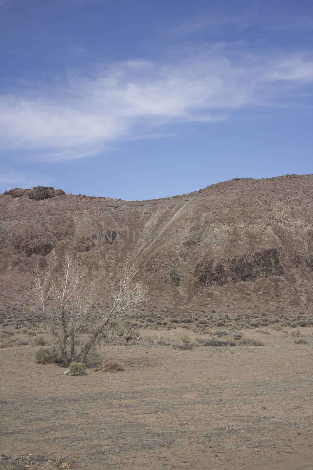 Desert mountain with blue skies and random clouds.