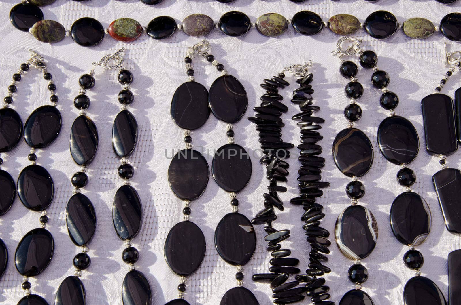 Dark black jewelry necklace closeup on table selling in outdoor fair market.