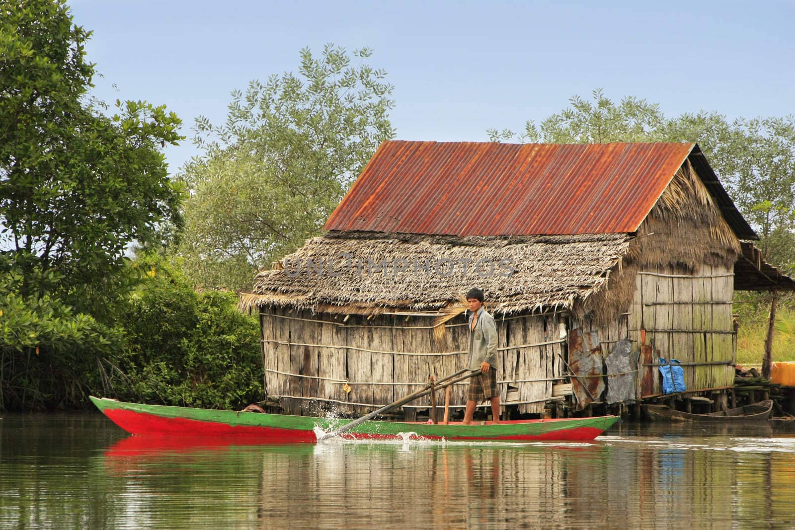 Local man rowing through water village, Ream National Park, Cambodia, Southeast Asia