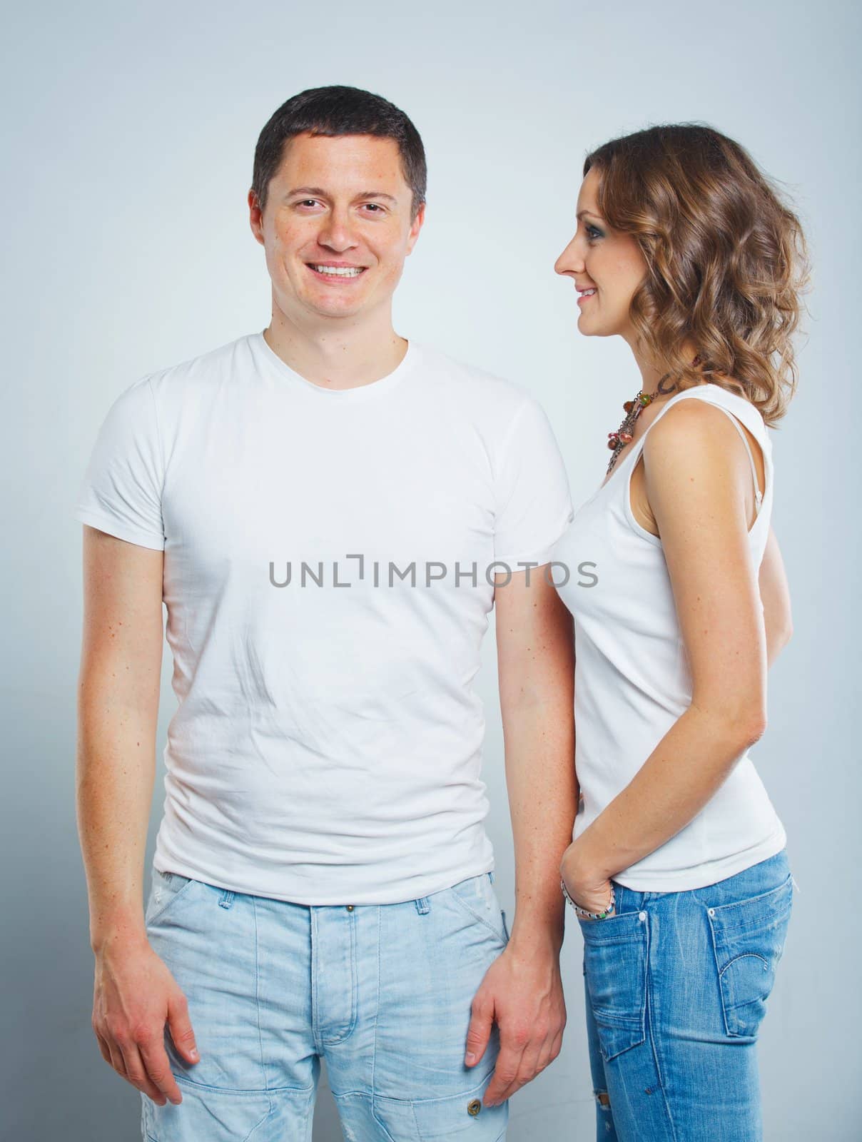 Happy beautiful young couple in love in white casual clothing. In the studio