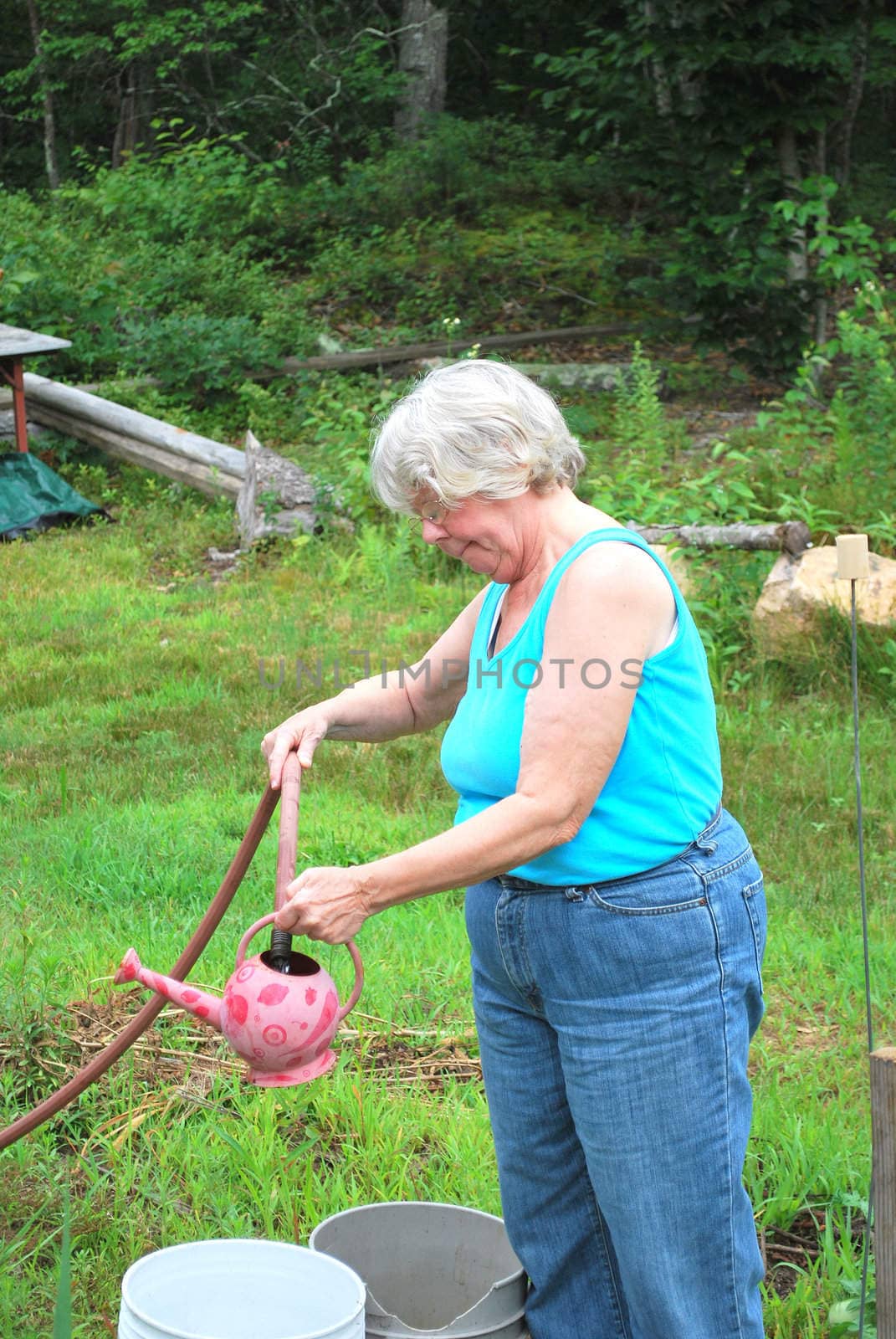 Mature female watering plants at home.