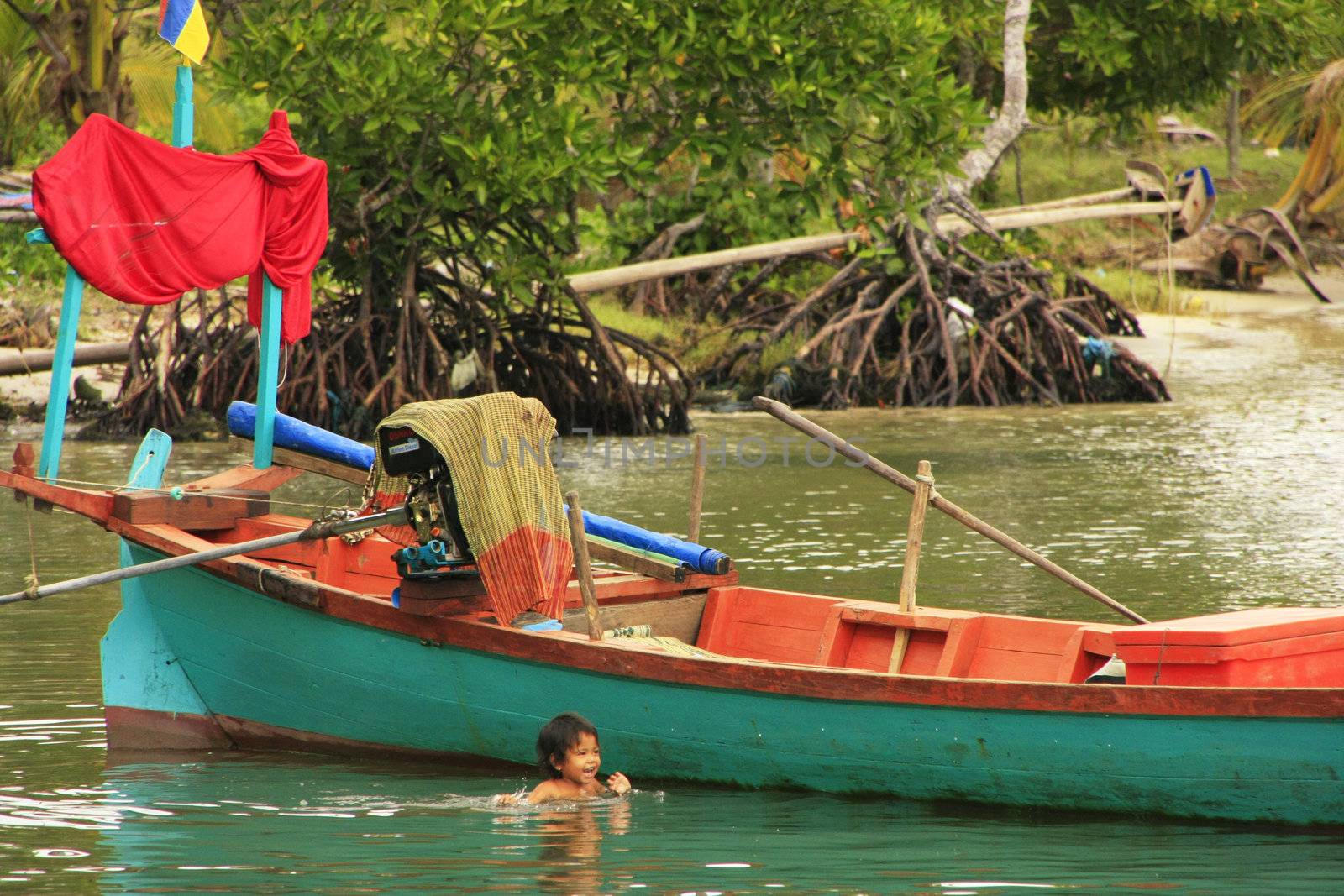 Child swimming near boat, Ream National Park, Cambodia, Southeast Asia