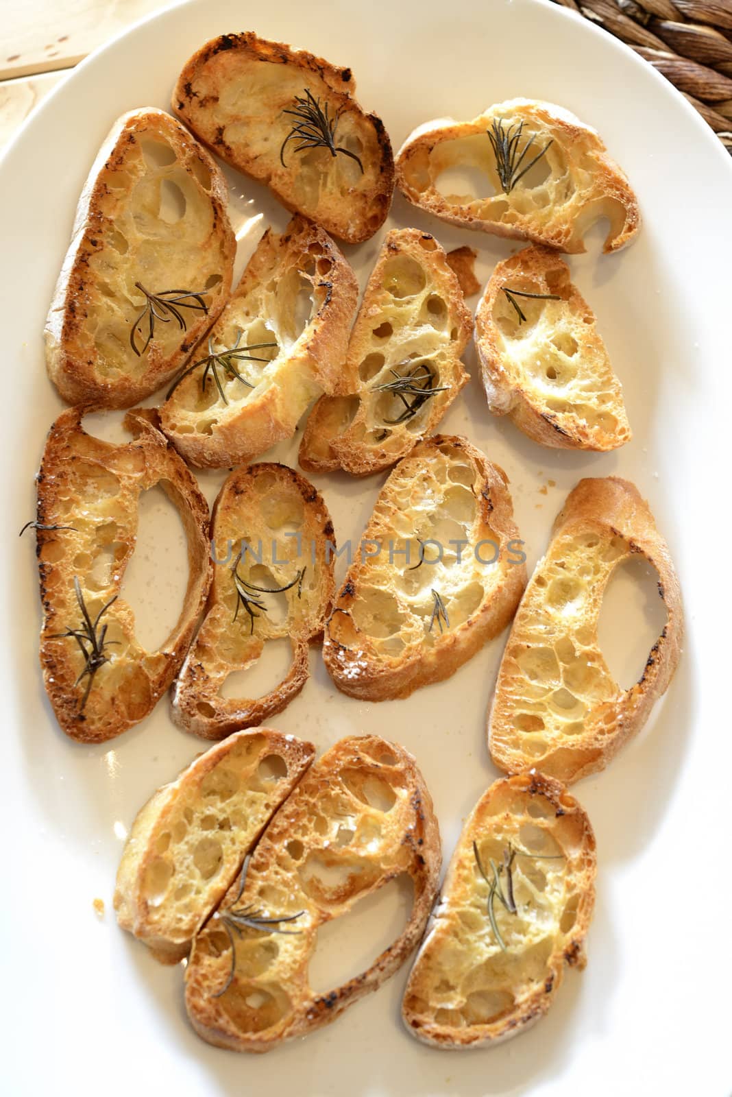 Garlic bread with herbs, on white bread dish