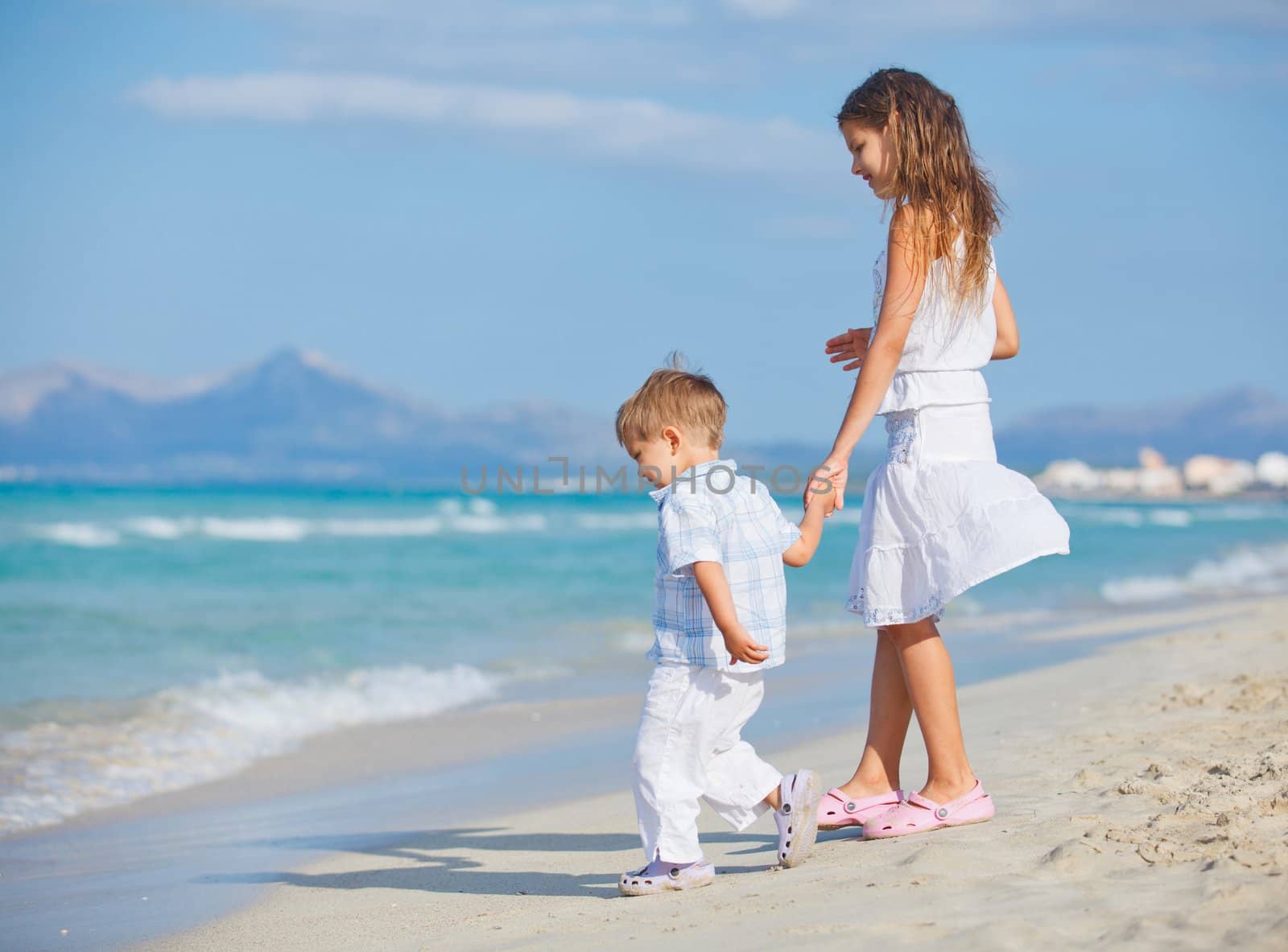 Young beautiful girl and boy playing happily at pretty beach. Majorca