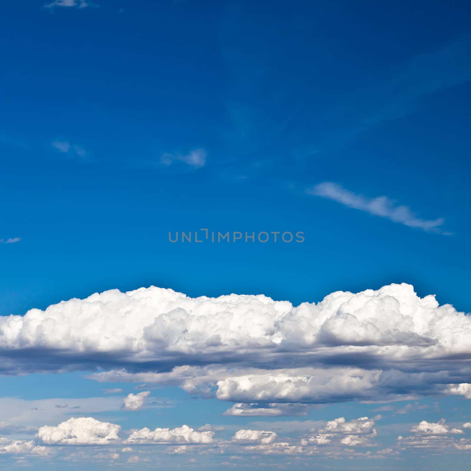 Blue summer sky with low white clouds with copy space