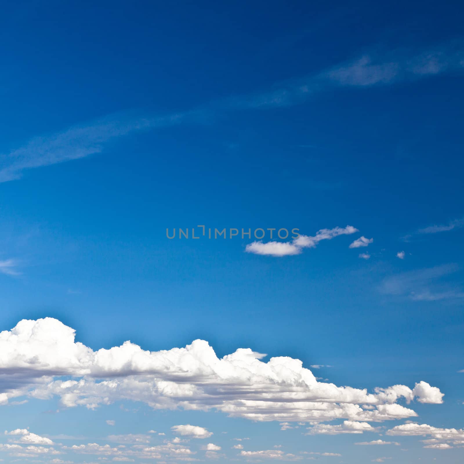 Blue summer sky with low white clouds with copy space