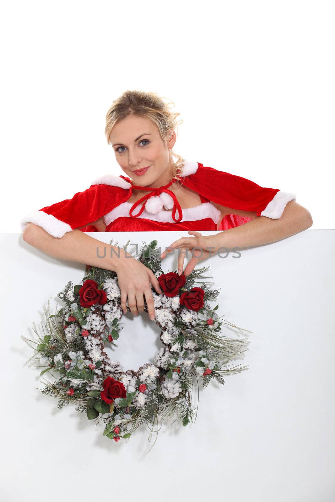 Woman dressed as Mrs. Claus and holding a wreath