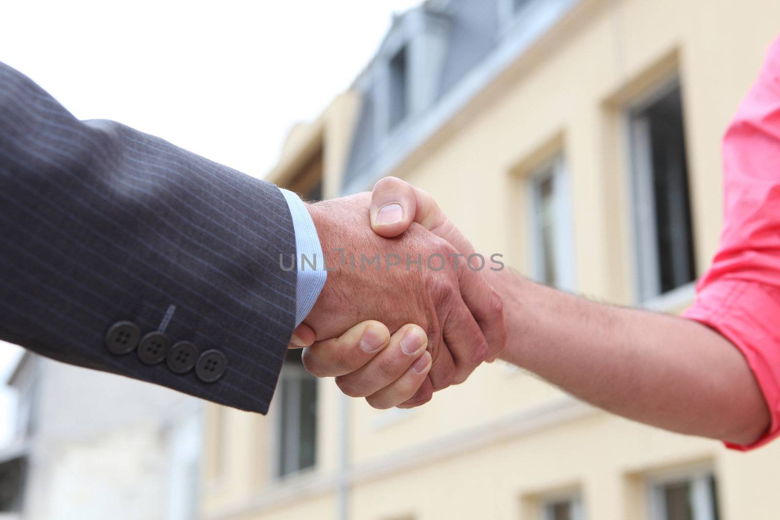 Couple shaking hands outside a house