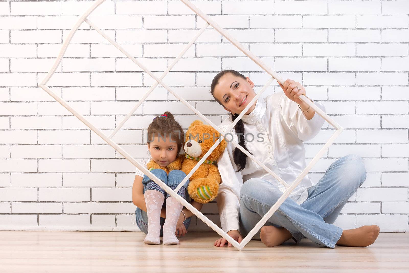 Mother and 5 year old daughter sitting by the wall by victosha