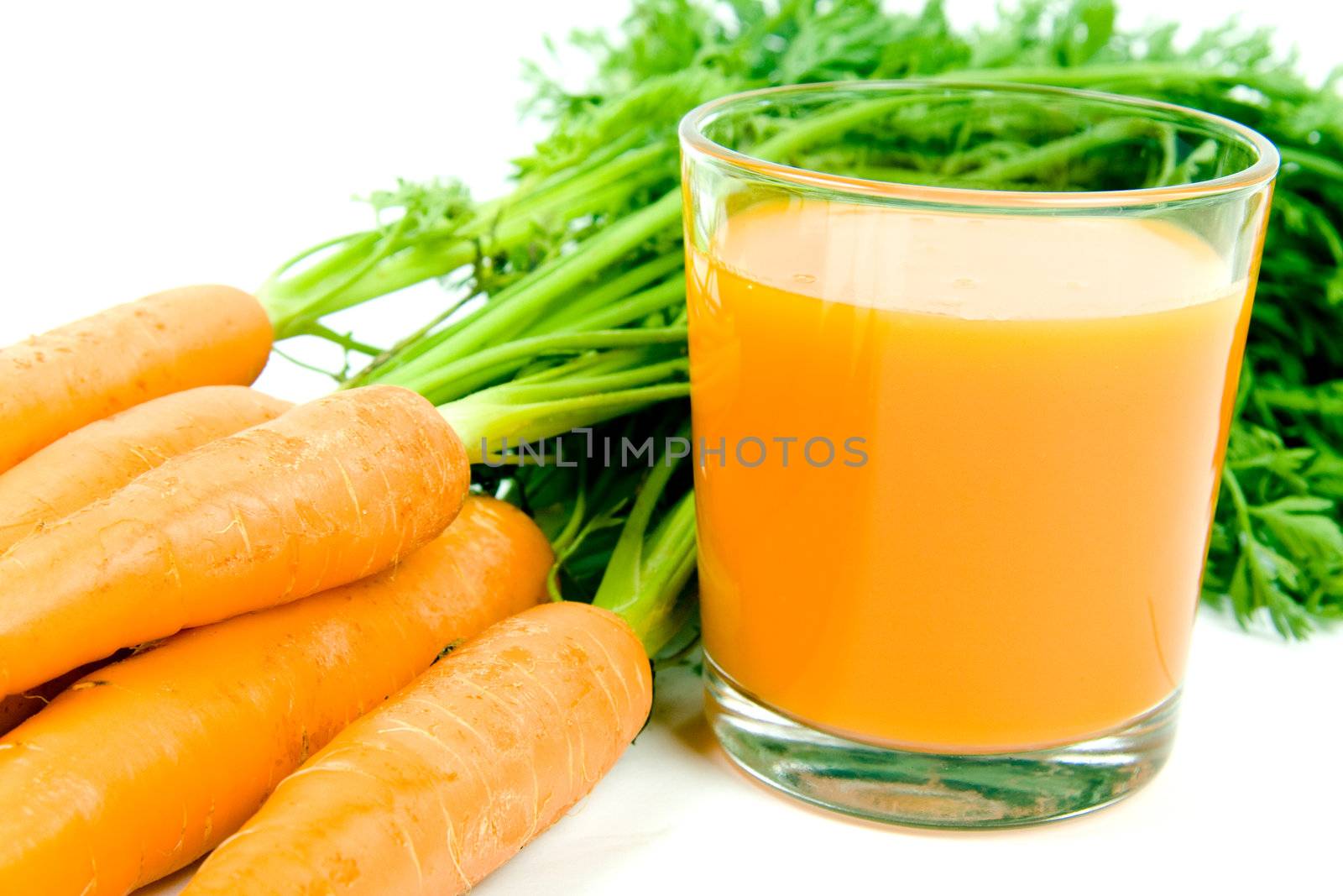 Fresh and ripe bunch of orange carrots with juice glass isolated on white background