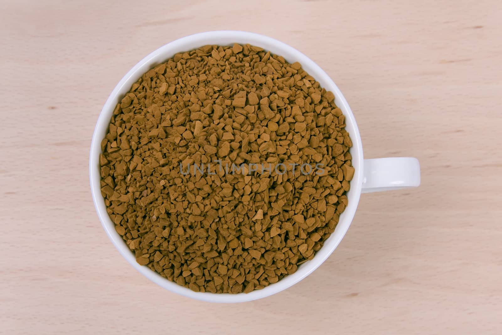 Coffee granules in a white cup on wooden background.