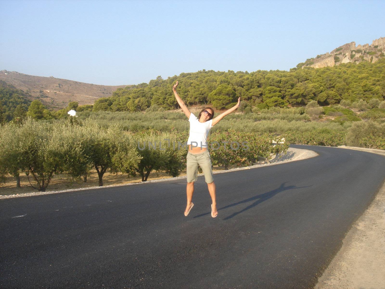 Pretty girl is jumping on countryside road                               