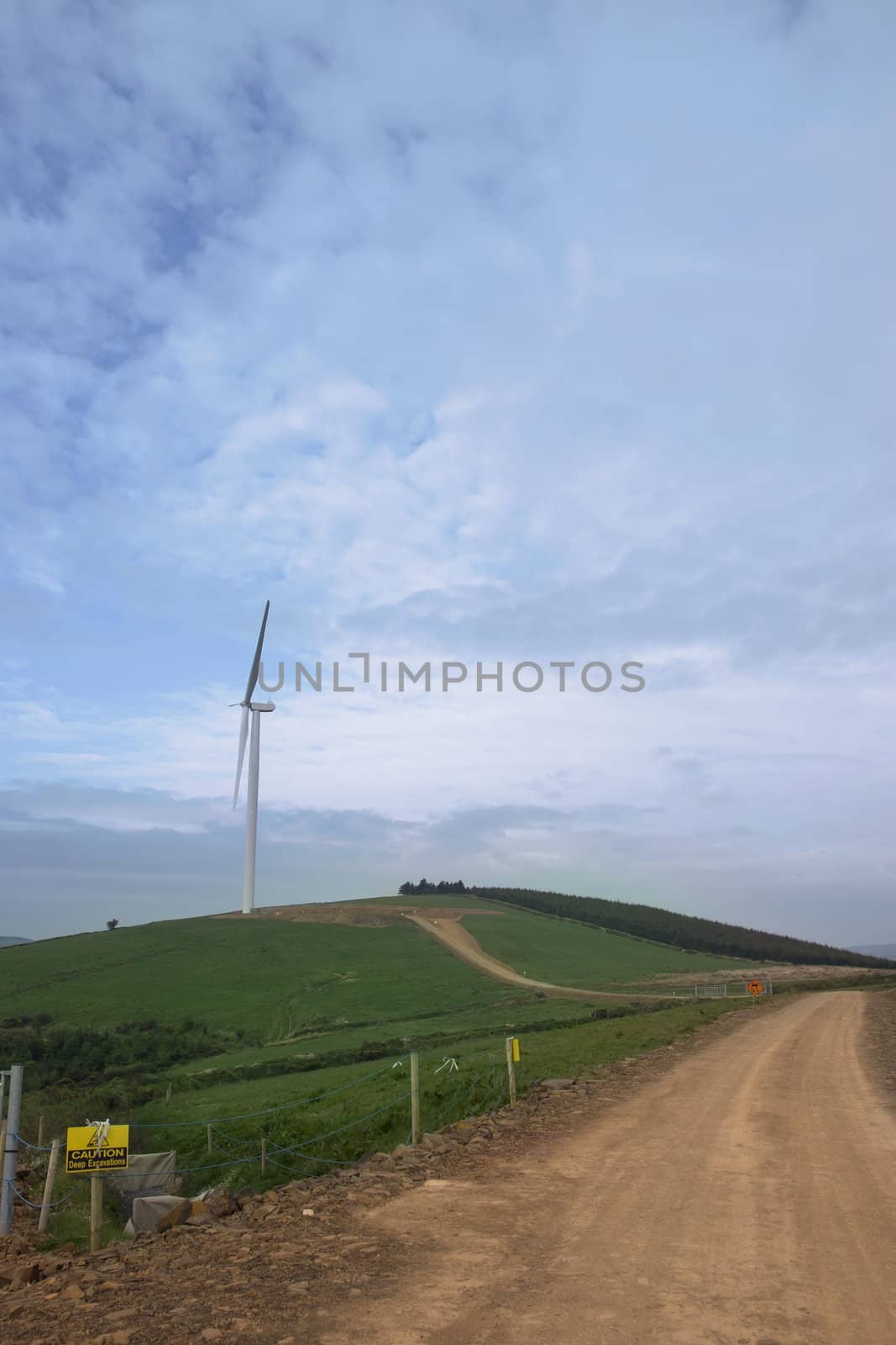 dirt road to a windmill on lush irish countryside landscape in glenough county tipperary ireland