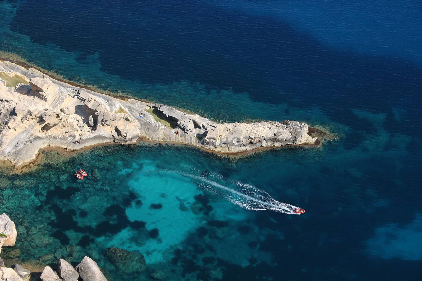 Aeriel view of three red boats floating on a turquoise Mediterranean Sea