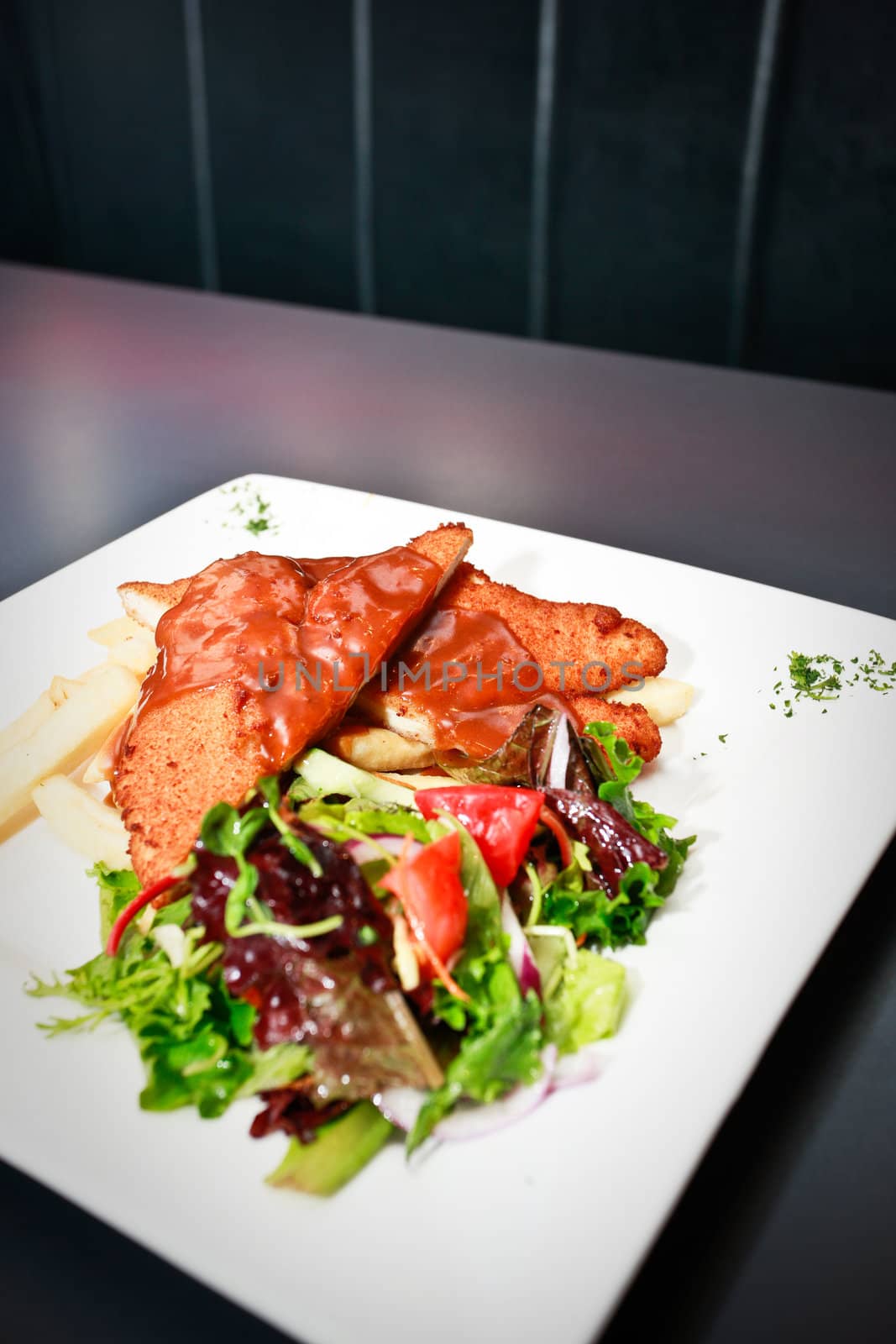 High angle view of portions of grilled chicken served with fresh green salads and potato chips for a delicious healthy meal