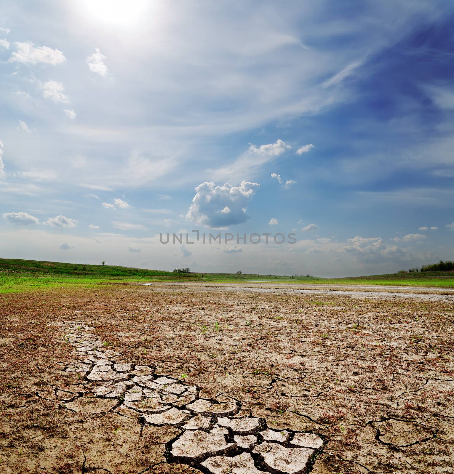 dramatic sky over dry cracked earth by mycola