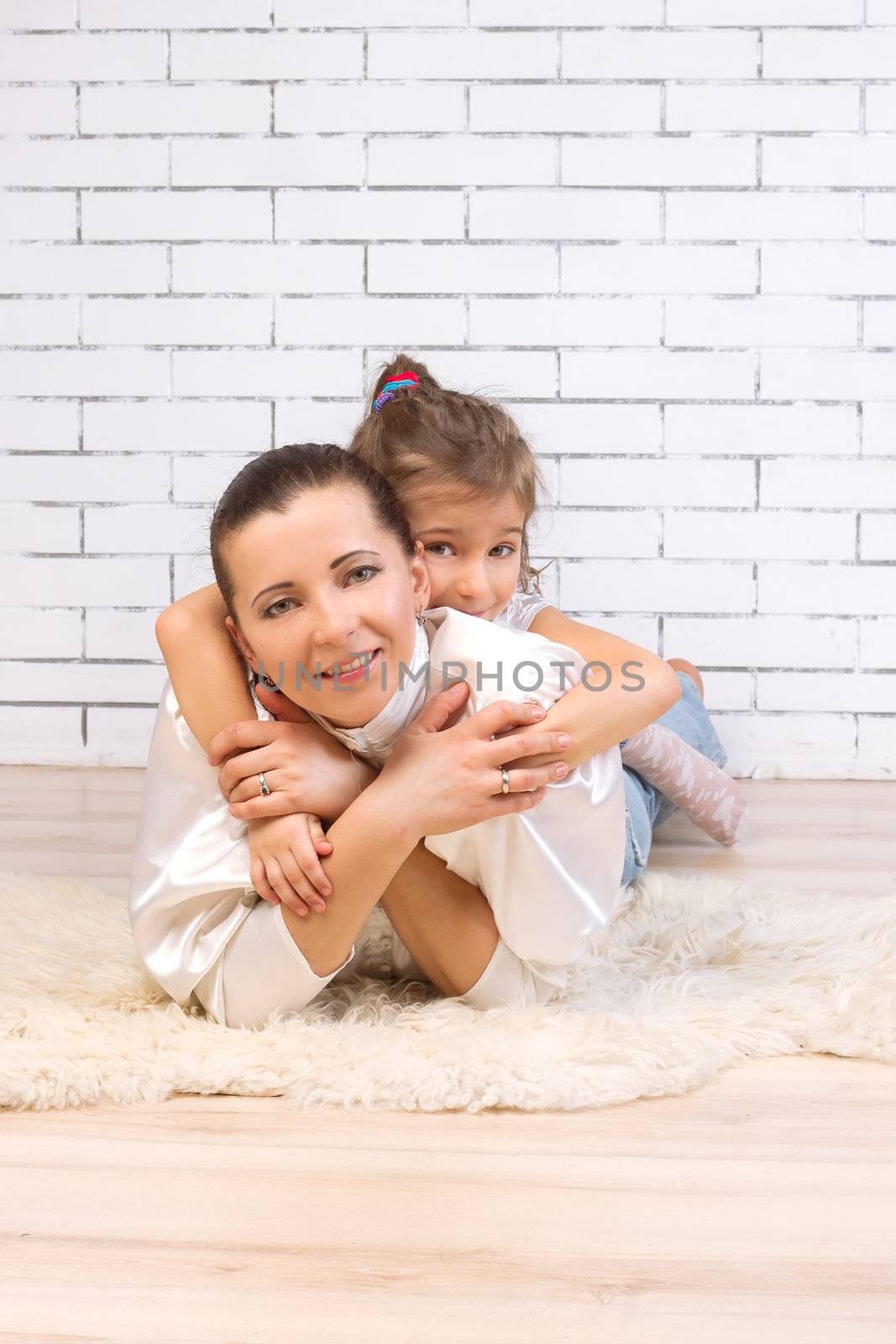 5 year old daughter riding on her mother hugging her against the wall