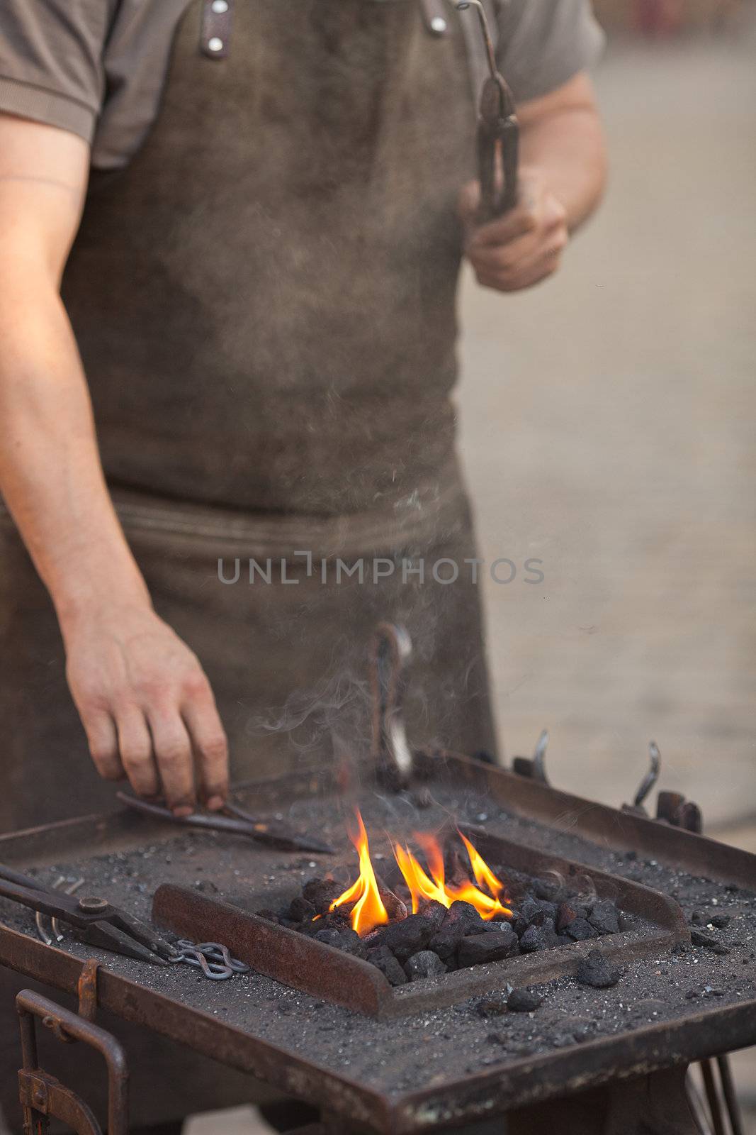 embers, fire, smoke, tools and the hands of a blacksmith