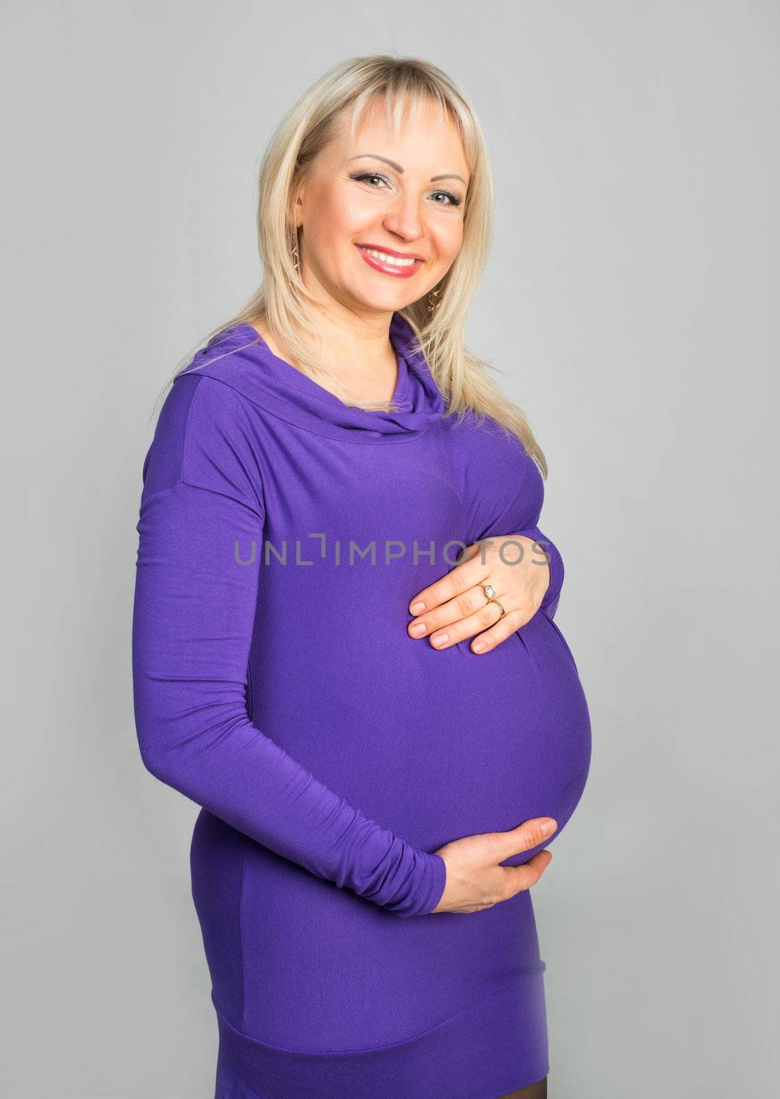 Smiling pregnant woman touching her belly with hands