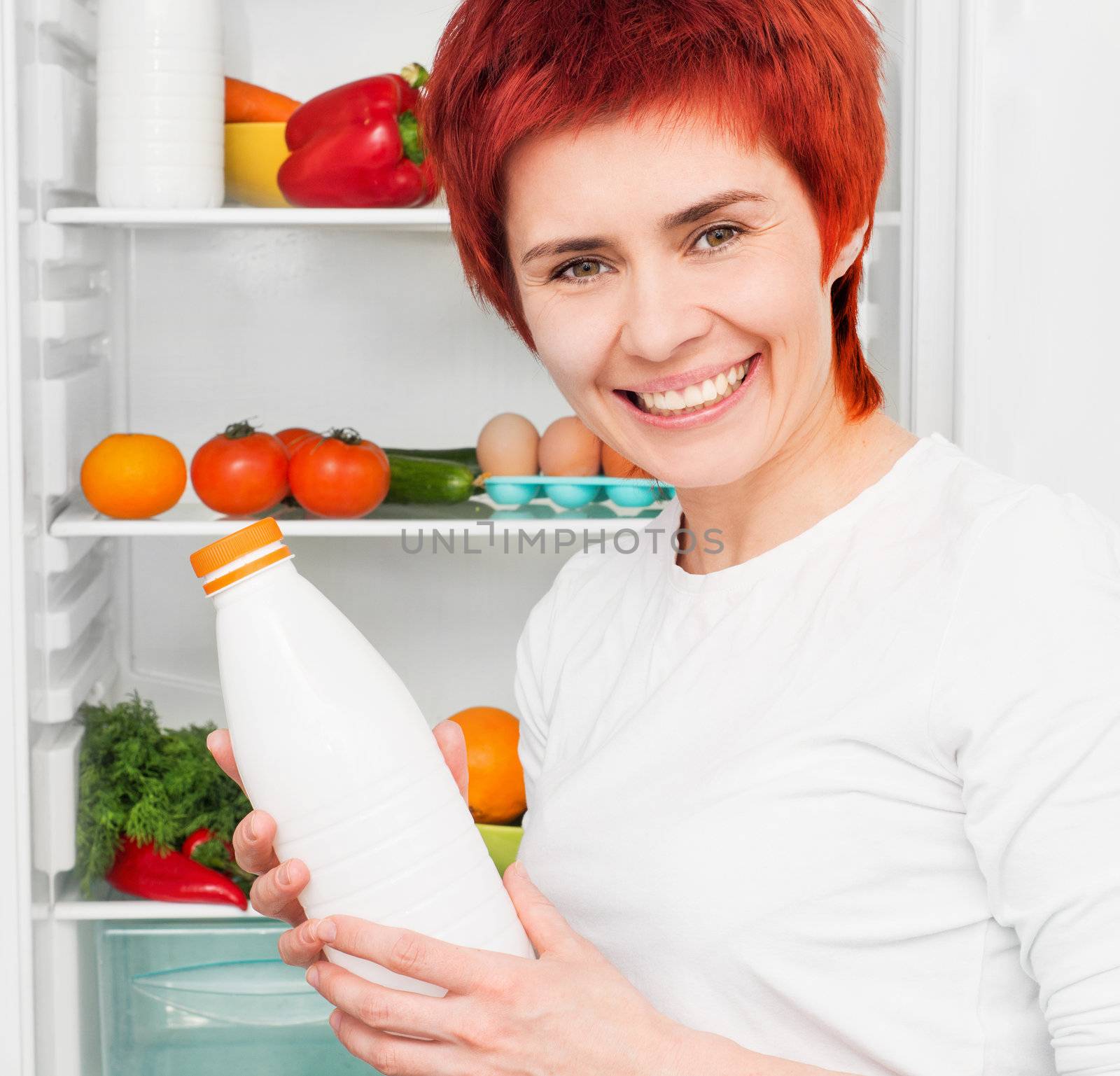 young woman with milk against the refrigerator with food