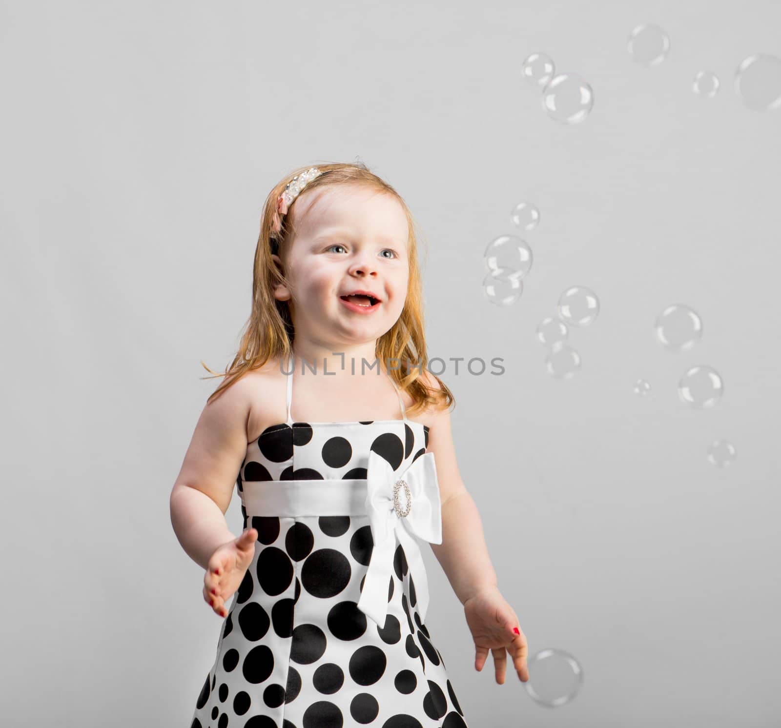 nice little girl with soap bubbles in studio