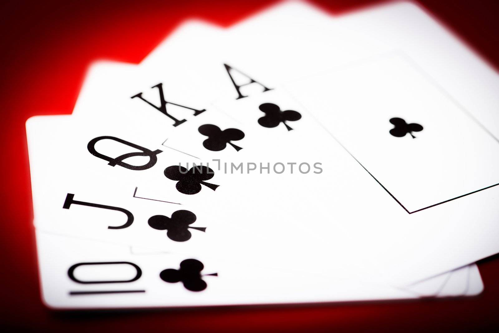 Royal flash of clubs on red poker table