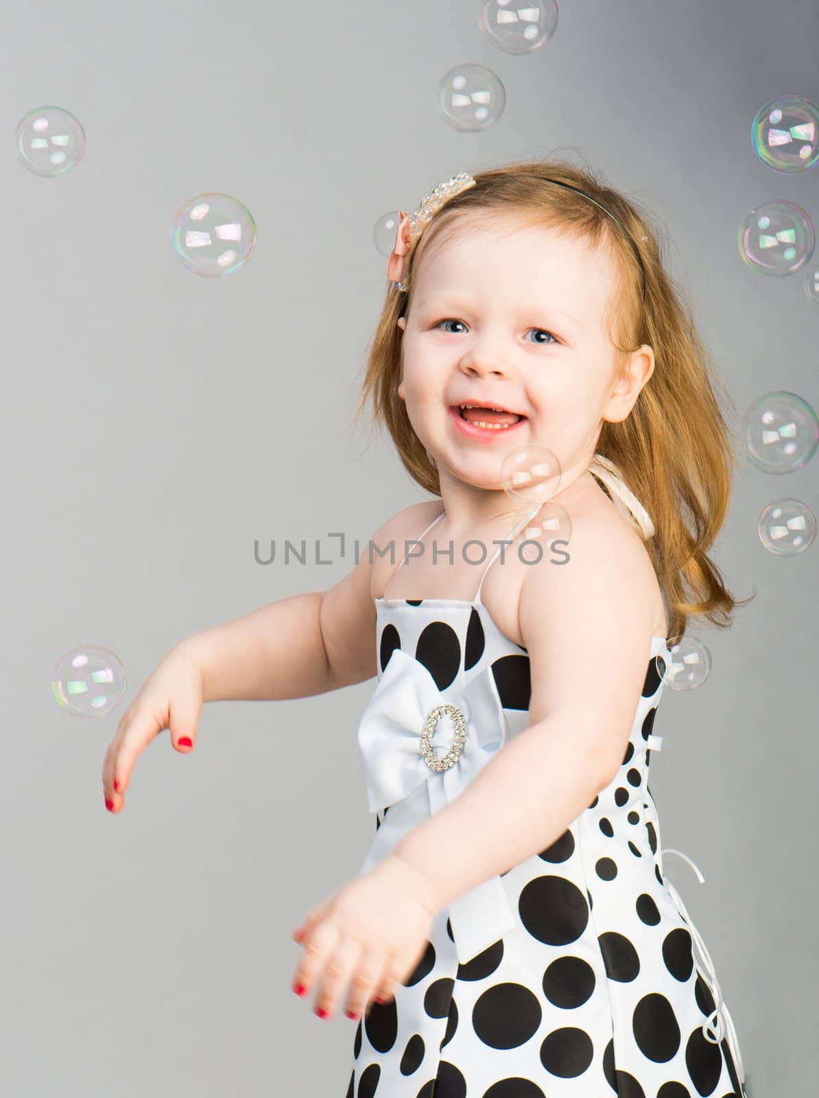 smilingl ittle girl with soap bubbles in studio