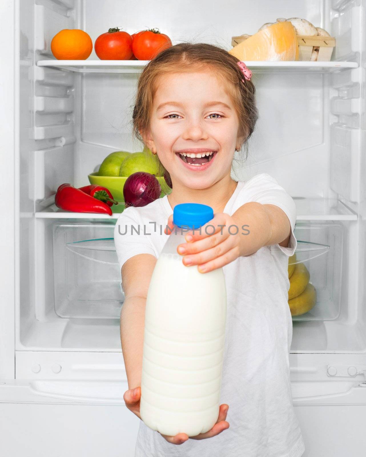 little girl with orange against a refrigerator with food