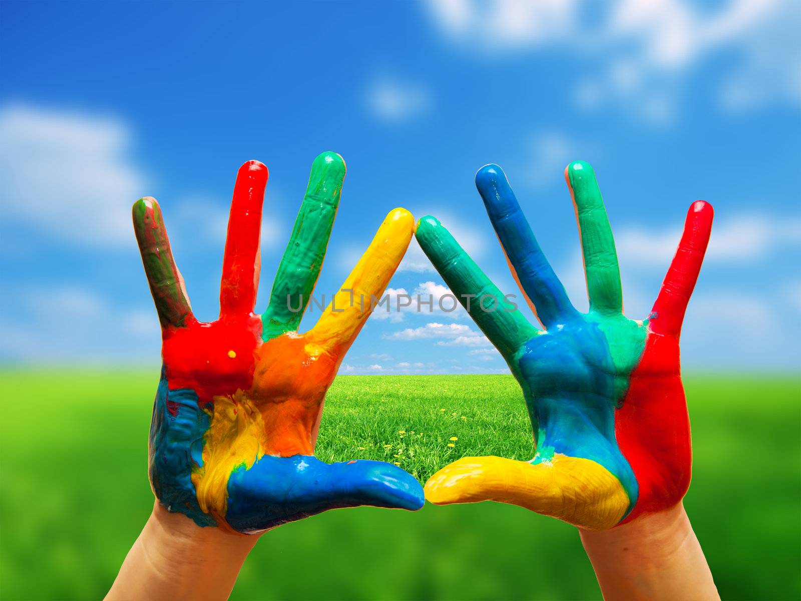 Painted colorful hands showing way to clear happy life, conceptual. Sunny perfect landscape