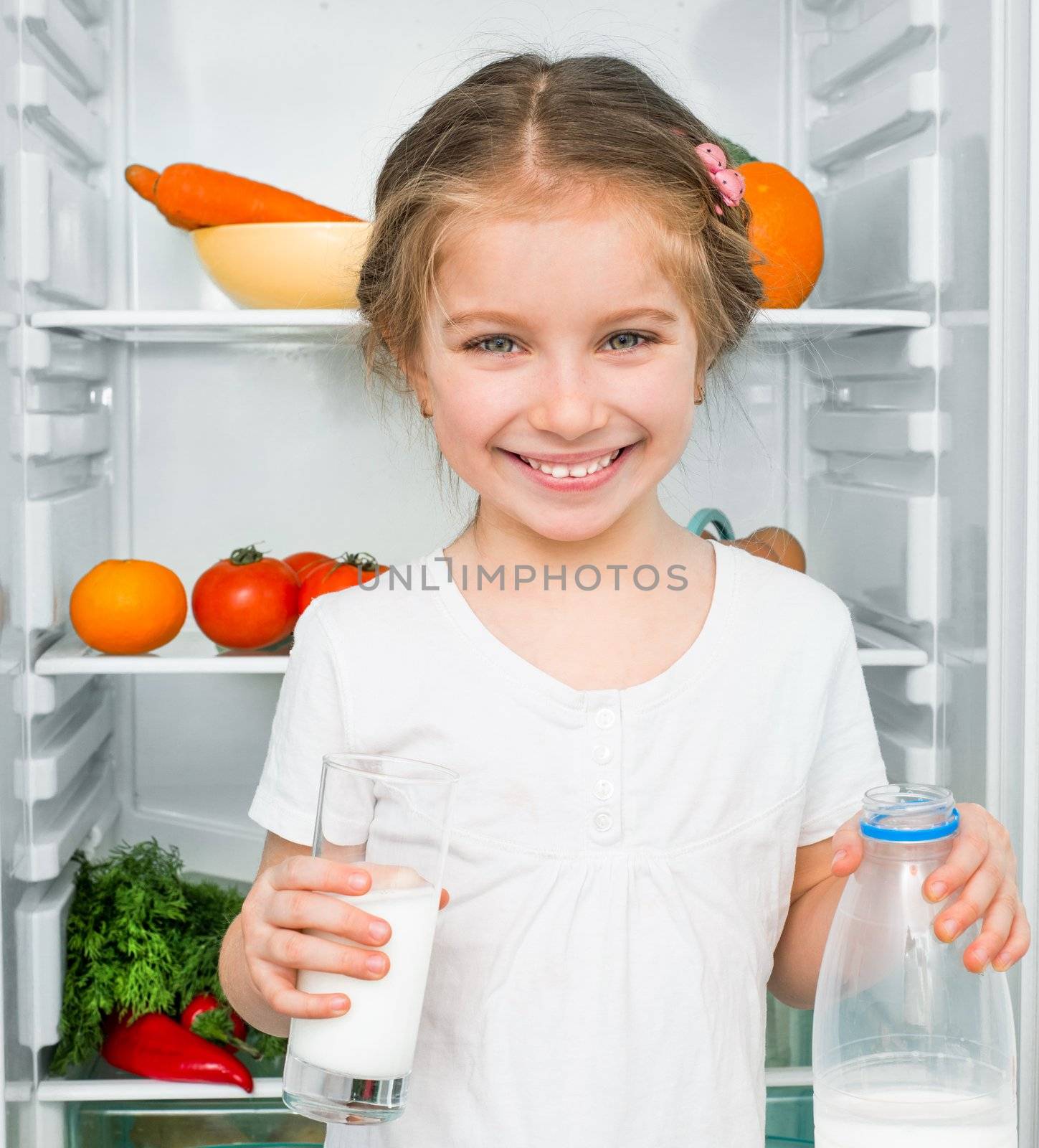 little girl with milk against a refrigerator with food