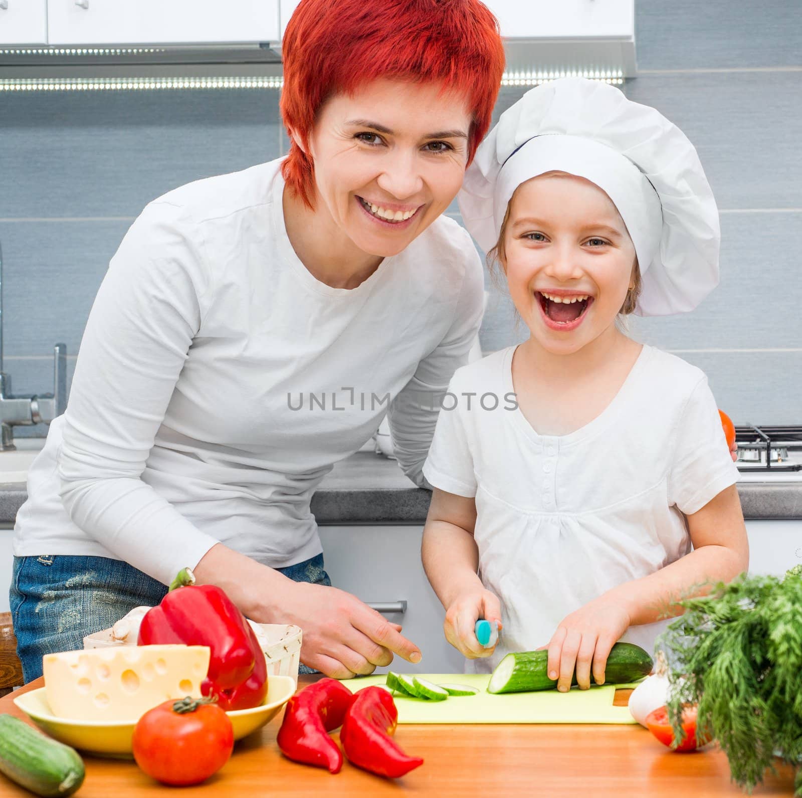 Mother and daughter in the kitchen cutting cucumber