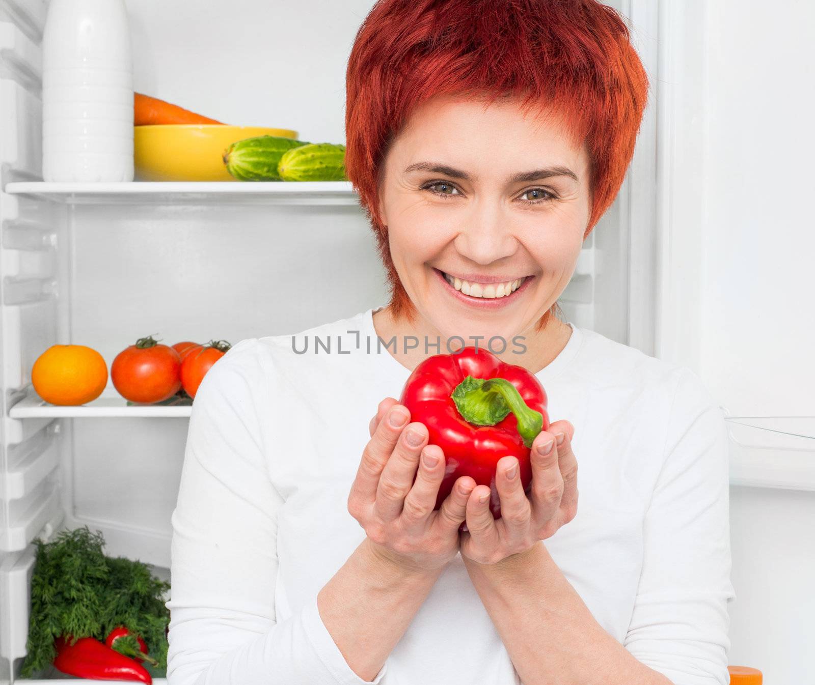 young woman with papper against the refrigerator with food