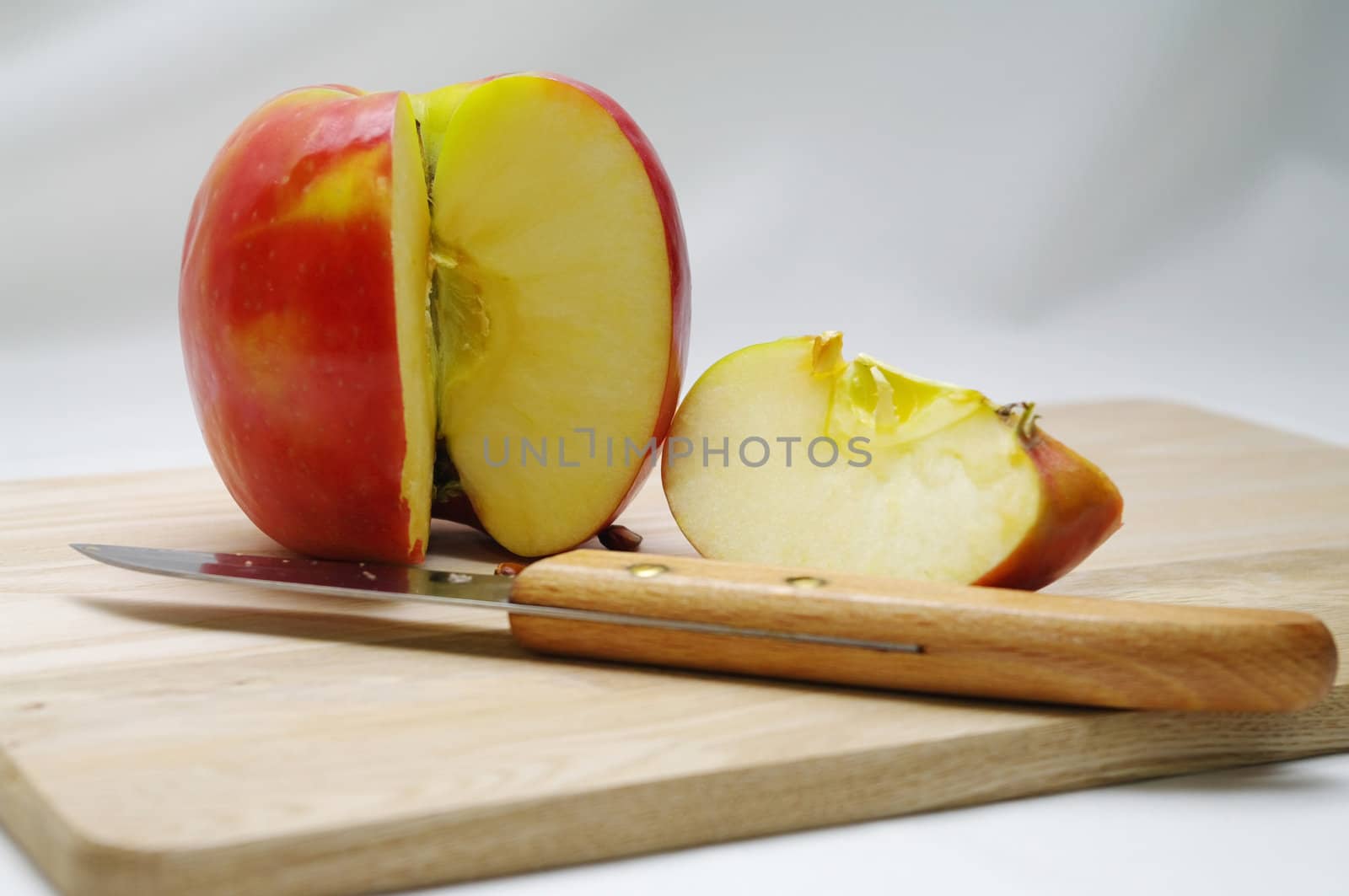An apple sliced ready for eating with a knife