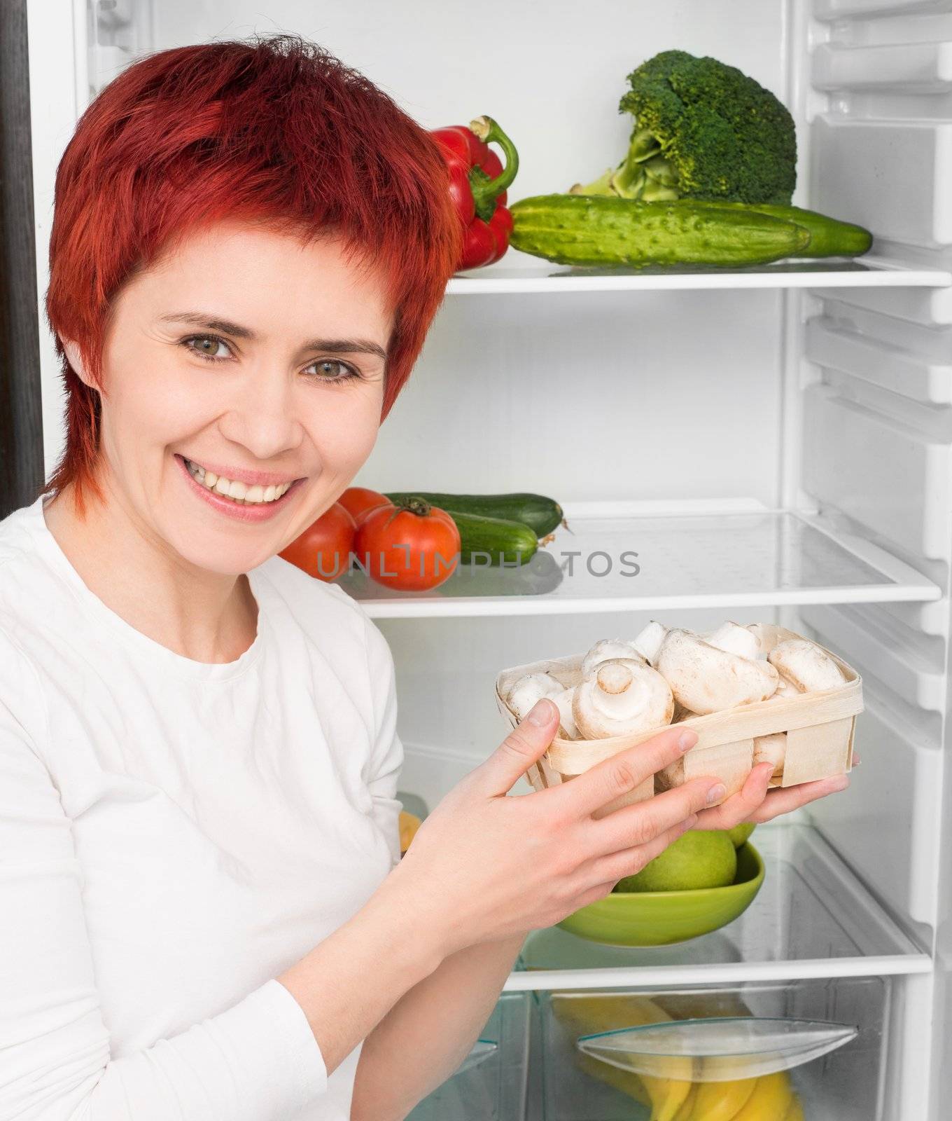 young woman with mushroom against the refrigerator with food