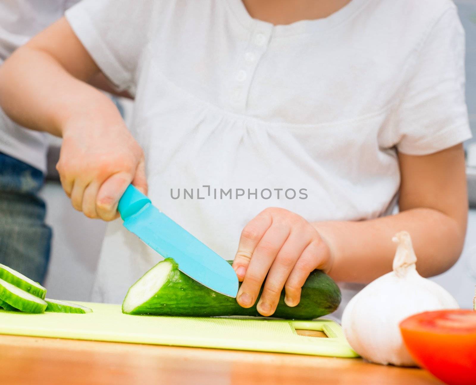 little girl cucumber slices on a cutting board