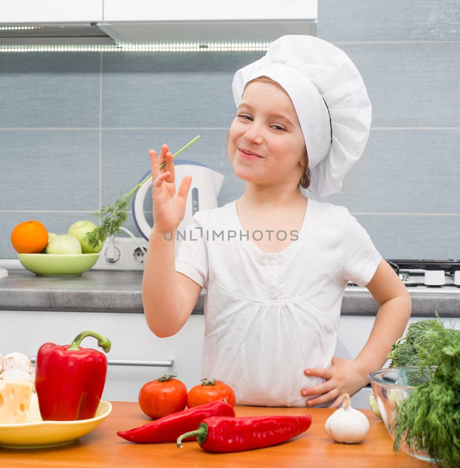 little girl in a cap chef in the kitchen with dill