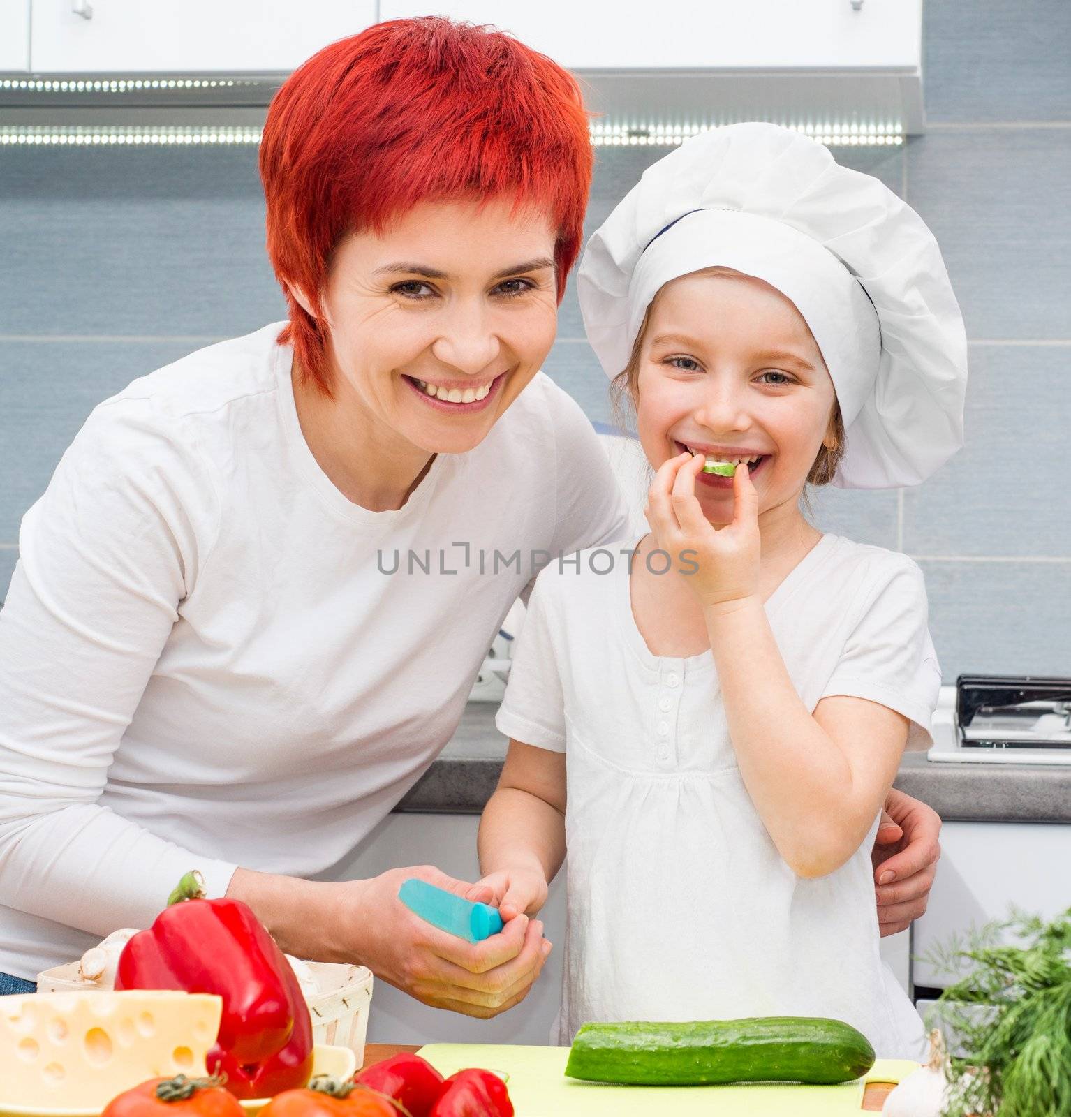 Mother and cute daughter in the kitchen with vegetables