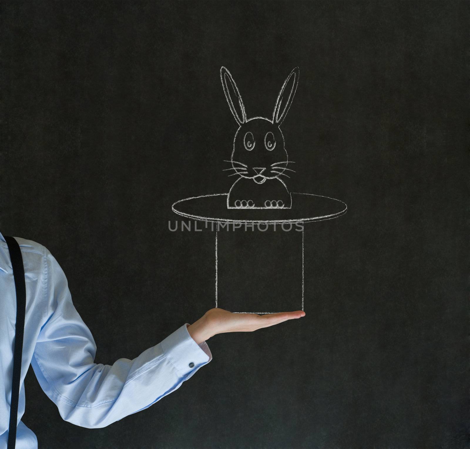 Man pulling rabbit from magic hat blackboard background by alistaircotton