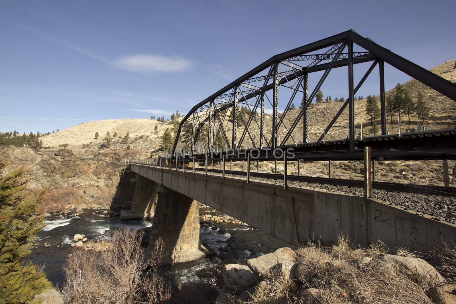 A train bridge in fall with blue skies and a river