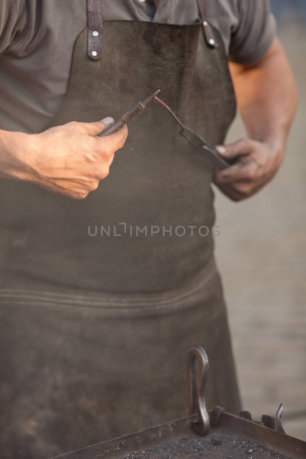 embers, fire, smoke, tools and the hands of a blacksmith