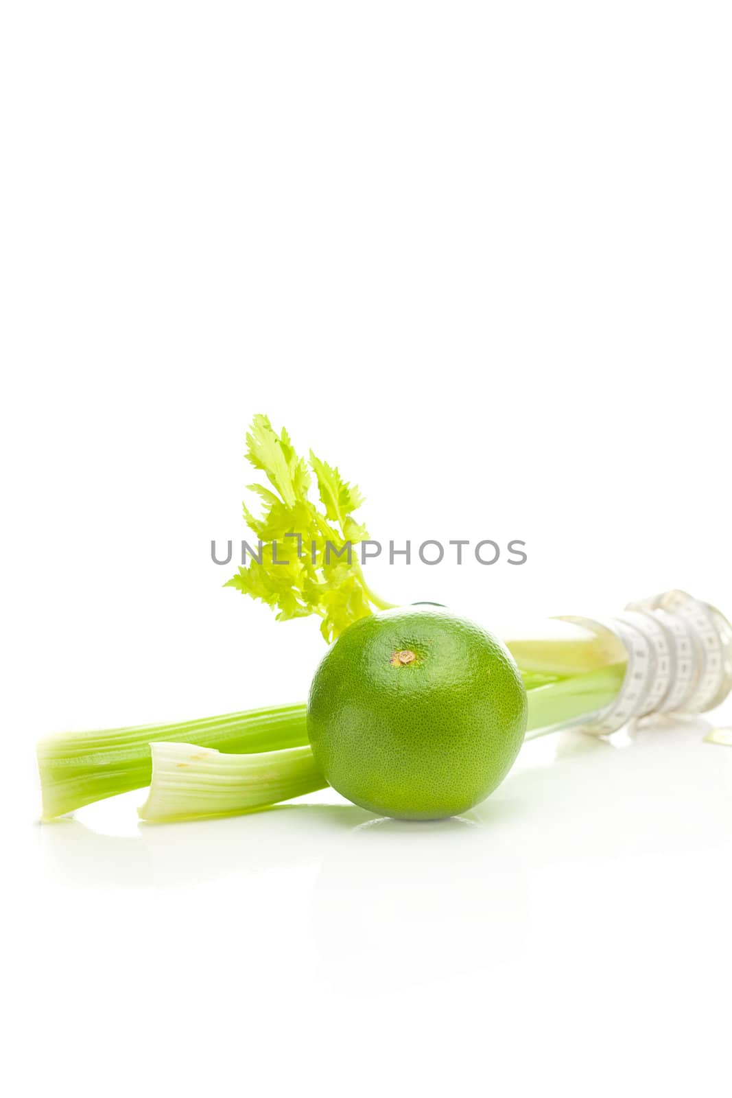 celery in a tall glass, green grapefruit and measure tape isolated on white