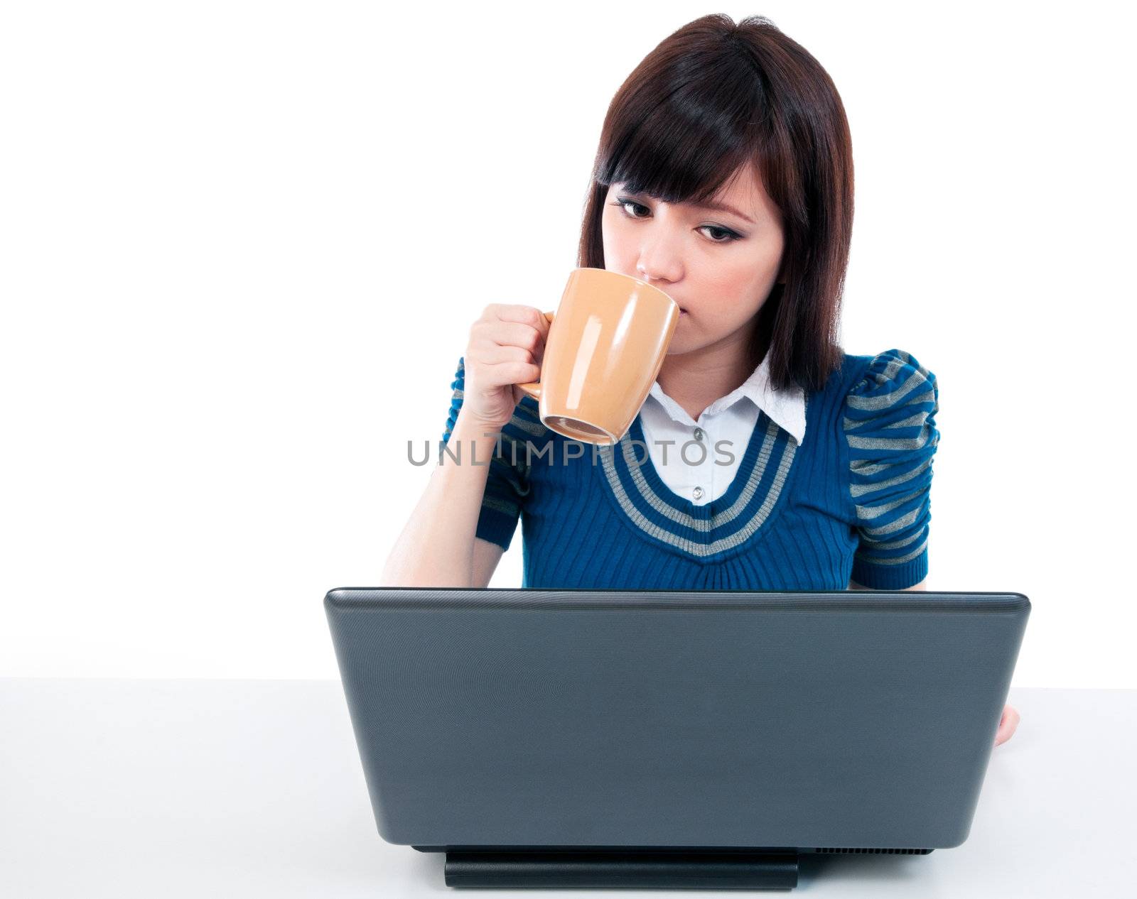 Portrait of a young Asian woman holding a cup and looking at laptop.