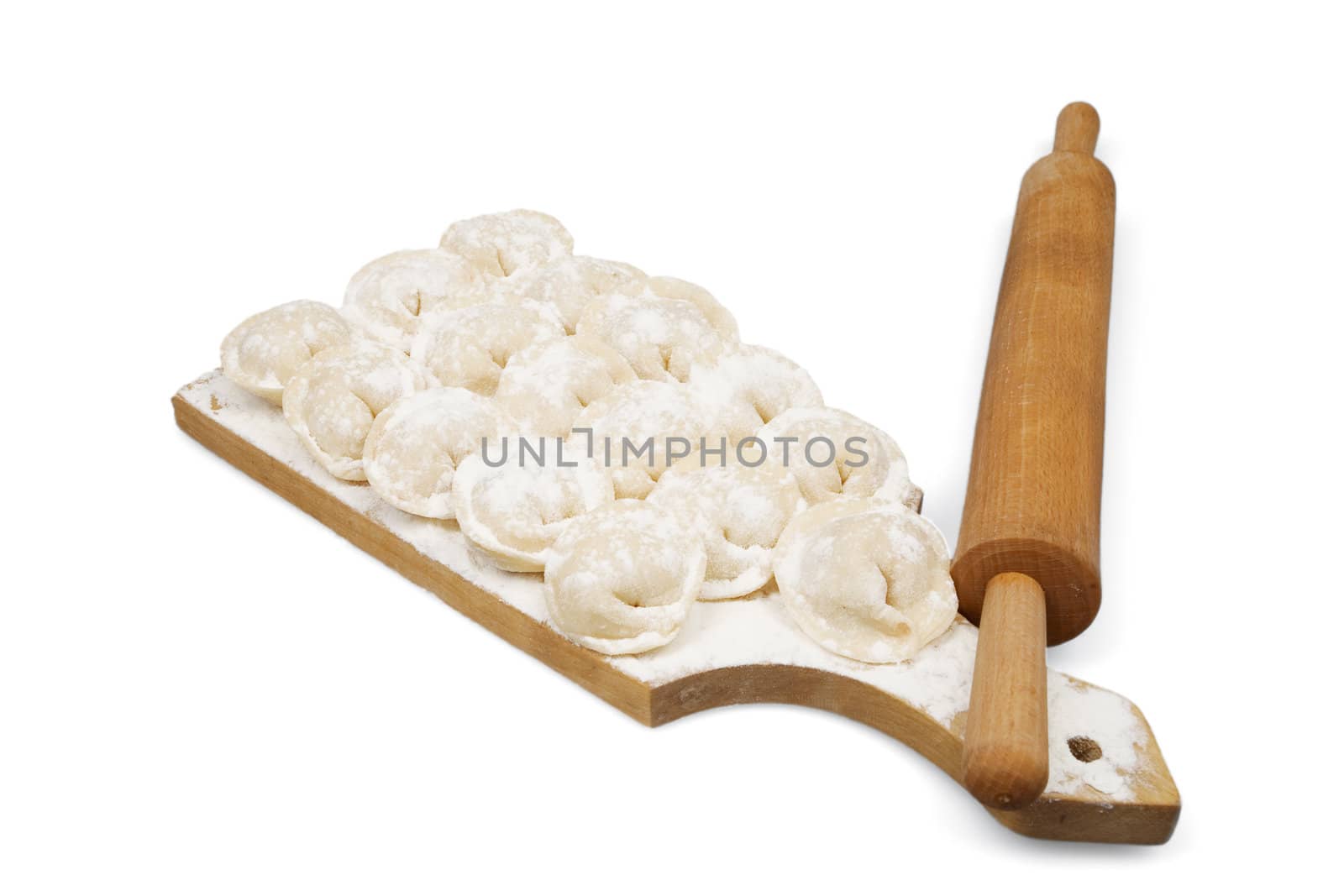 Raw ravioli and wooden stick on a white background