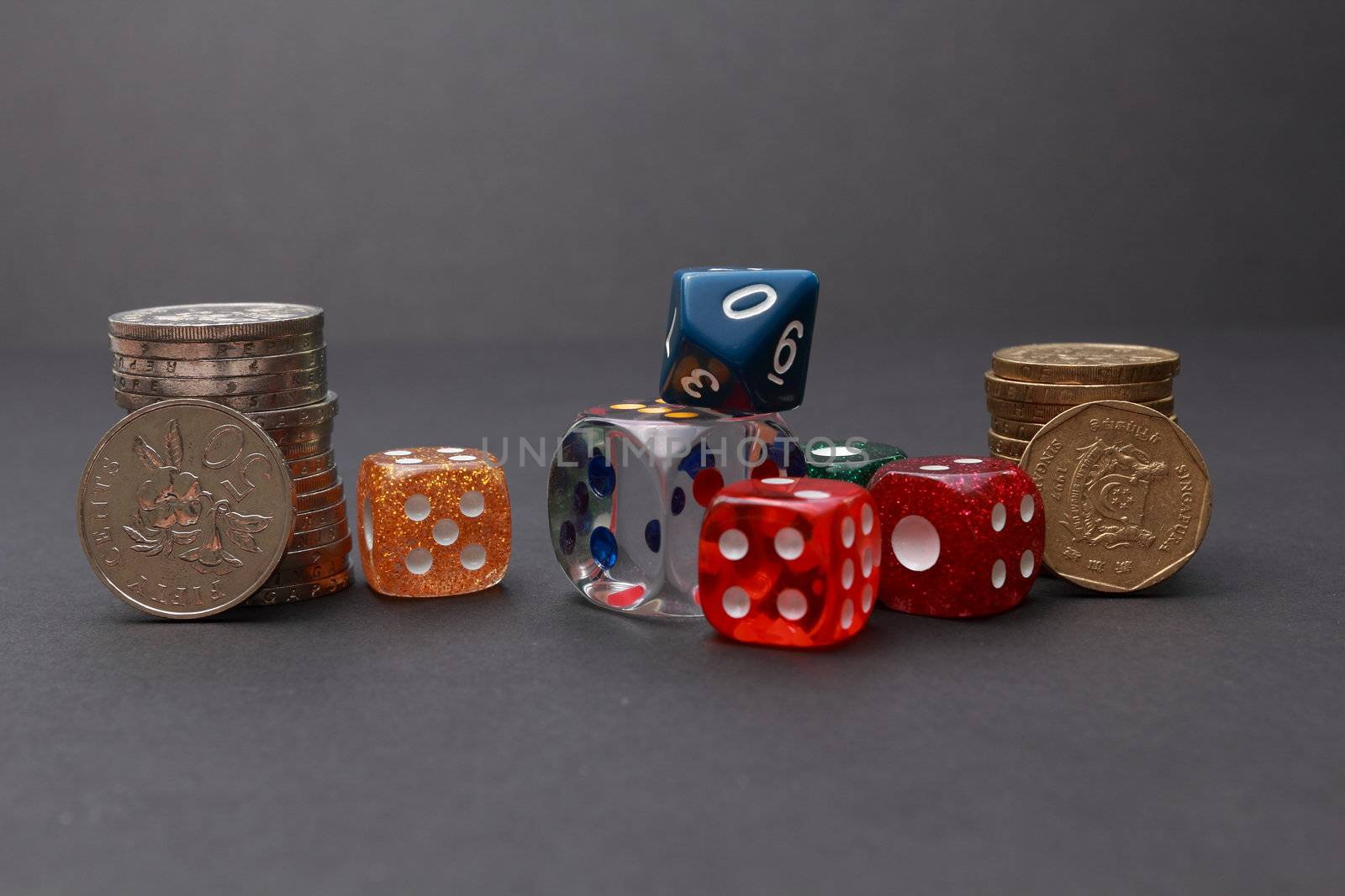 6 coloured dices with coins on dark background