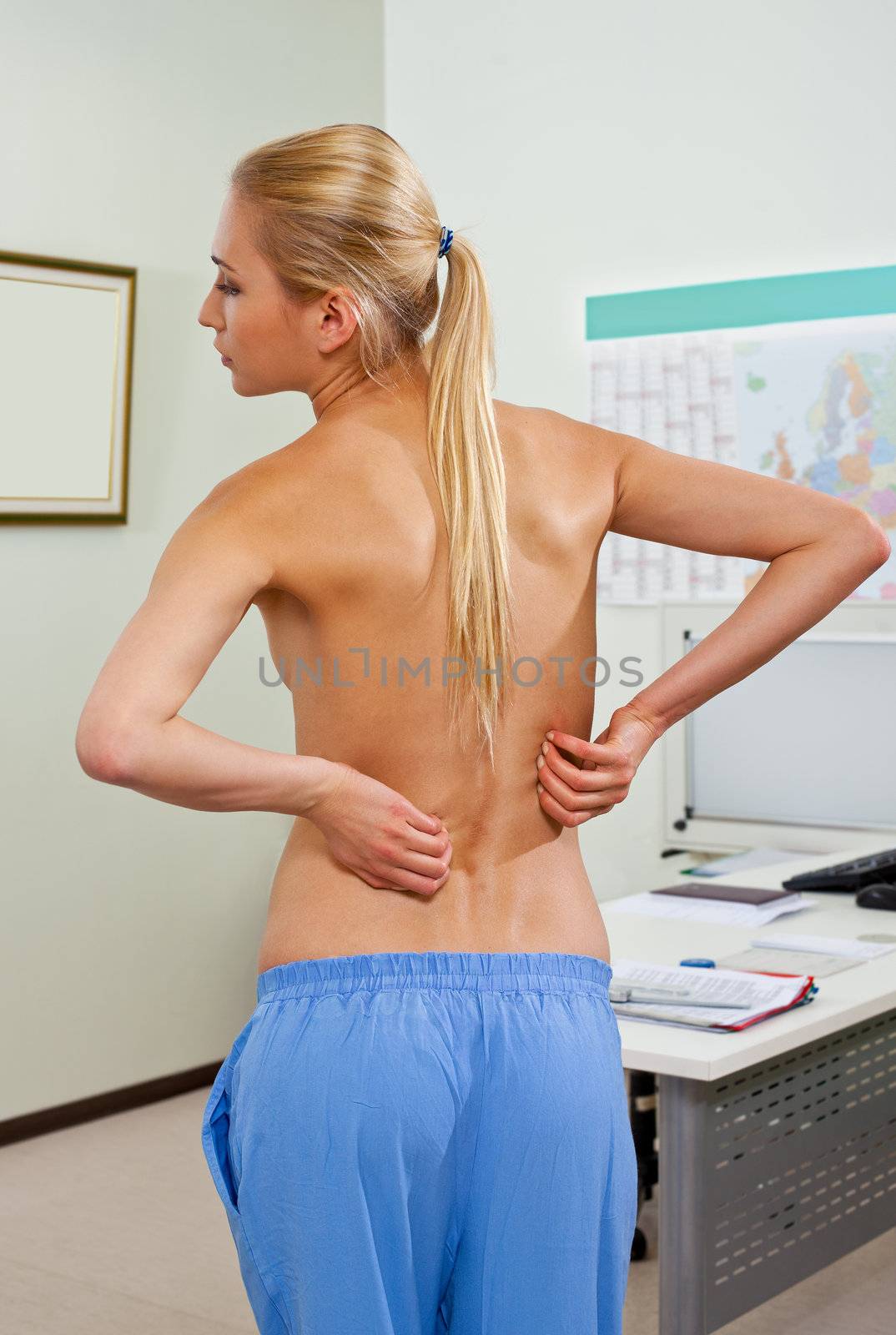 Topless female patient in doctors cabinet, with back pain