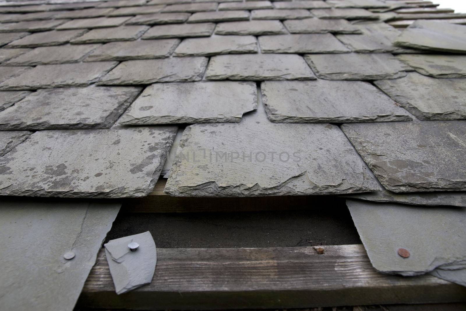 broken and fallen slate leaves hole in a roof due to storm or decay